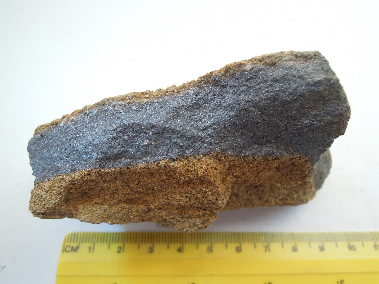 A broken piece of iron ore, dark metallic rock with a rusty face.